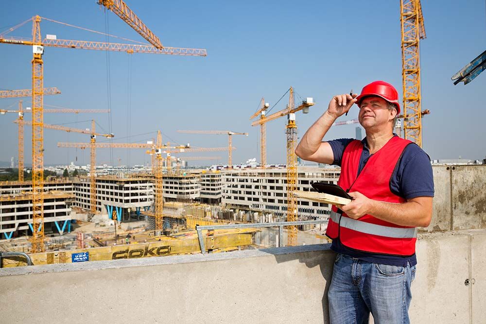 Brandschutzfachkraft auf einer Baustelle mit rotem Helm und Weste